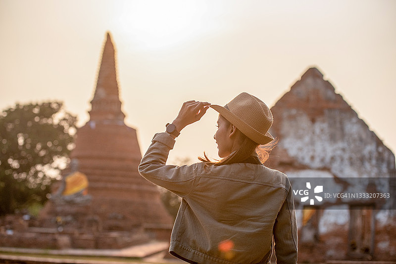 年轻漂亮的背包客在泰国阿瑜陀耶古迹旅行，用相机记录旅程图片素材