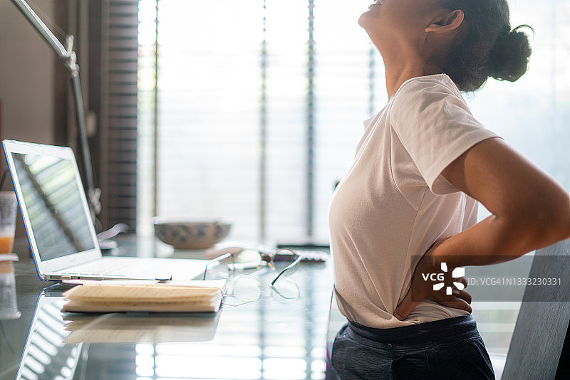 在家办公的妇女因坐在电脑桌前而背痛图片素材