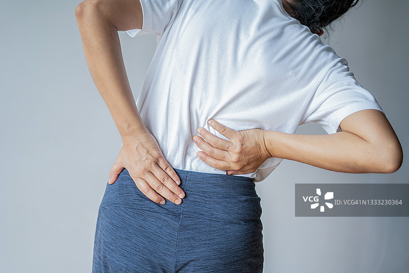 疲惫的女人感到颈部疼痛，按摩紧张的肌肉，背痛和下背部图片素材