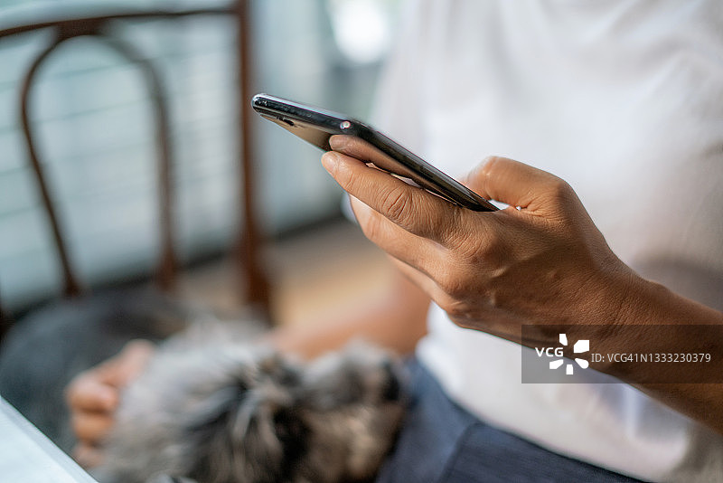 女人手持手机在家使用移动设备应用程序特写图片素材