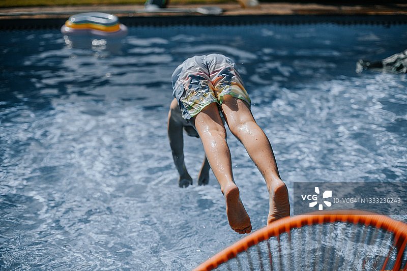 男孩跳入游泳池的后视图图片素材