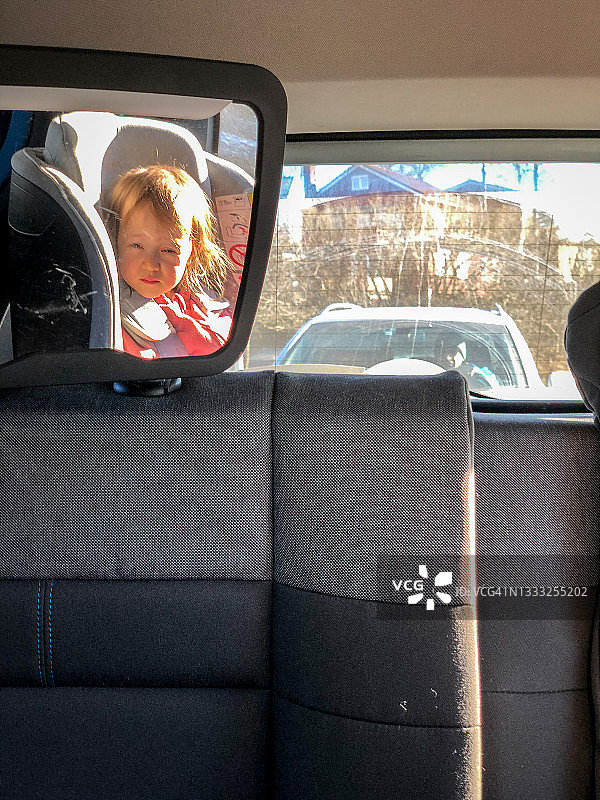 小女孩在驾驶员遮阳板后视镜旁图片素材