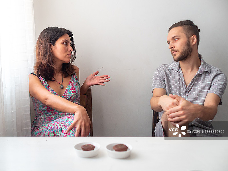 在哥伦比亚麦德林，拉丁裔女人在窗边看着白色房间里的白人男子图片素材