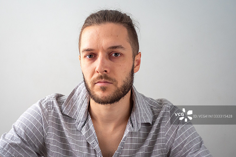 年轻的白人男子在白色背景下严肃地凝视图片素材