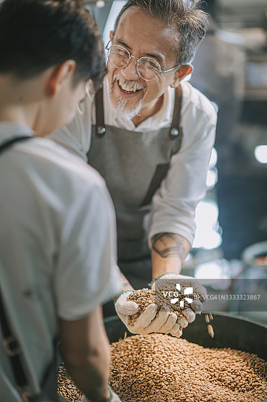 拿着一把生咖啡豆，满意咖啡质量，准备烘焙的老年男人图片素材