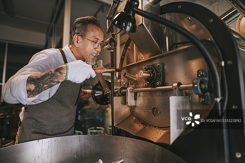 中国亚洲老年手工艺人在烘焙机中提取咖啡豆图片素材