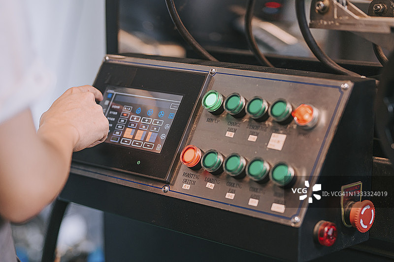 近距离观察中国工人操作咖啡烘焙机控制面板图片素材