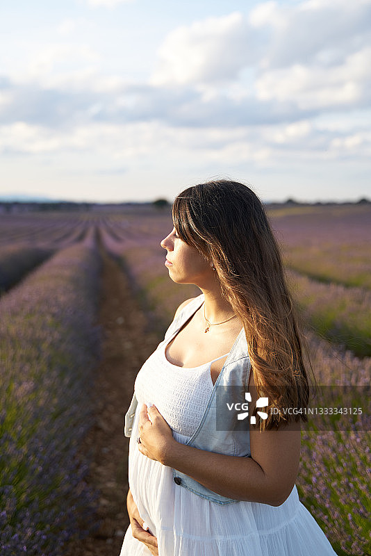 深色头发的女人站在薰衣草田中，看向远方图片素材