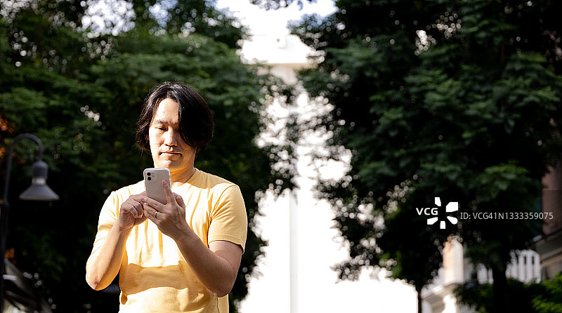 在公园里使用手机的亚洲男人图片素材