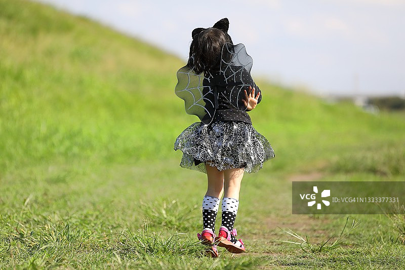 万圣节服装小女孩背影：黑色连衣裙、翅膀和耳朵图片素材