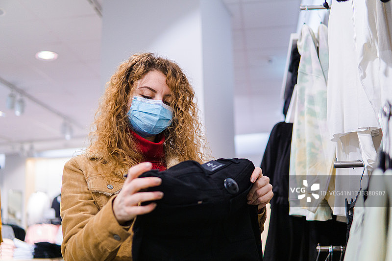 在服装店戴着口罩购物的女人，新常态图片素材