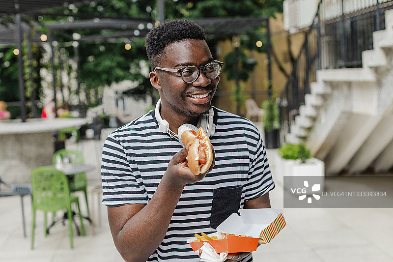 正在吃热狗的年轻非洲裔美国男子图片素材
