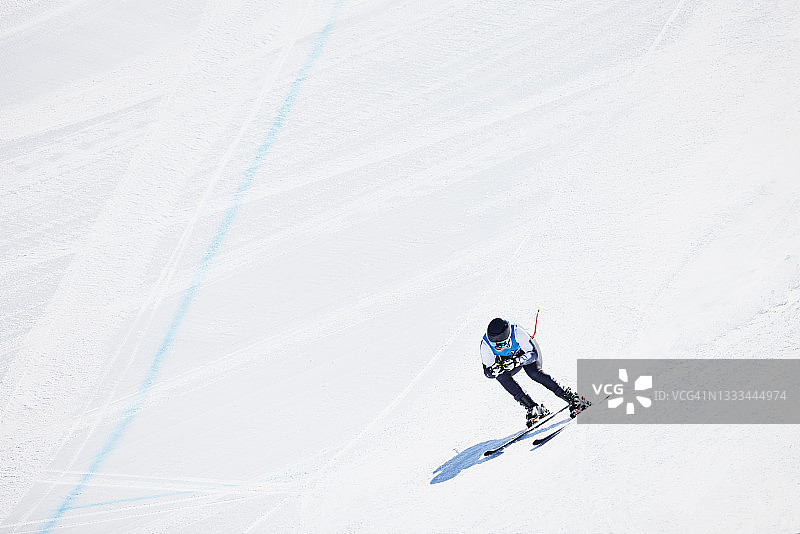 阳光明媚的冬日早晨，男子滑雪运动员在速降滑雪比赛中滑雪的广角镜头图片素材