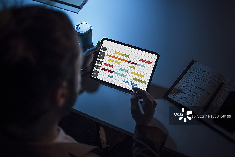 男人坐在办公桌前，使用平板电脑和数位笔（留白）图片素材