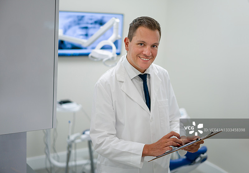 快乐的牙医在诊所工作并拿着病历图片素材