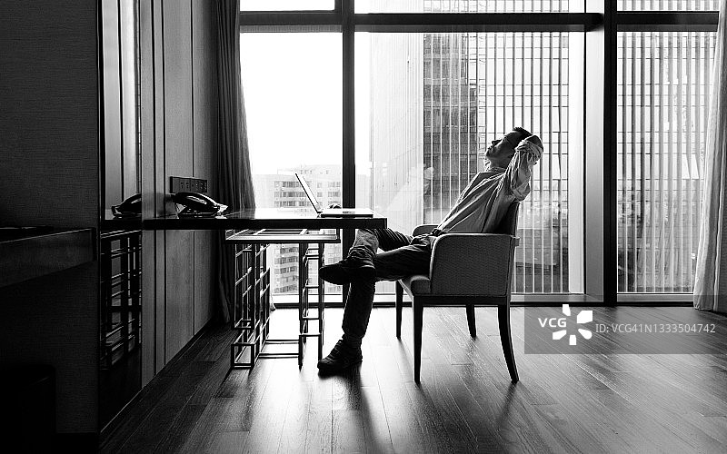 双手放在脑后倚靠在椅子上的商人图片素材