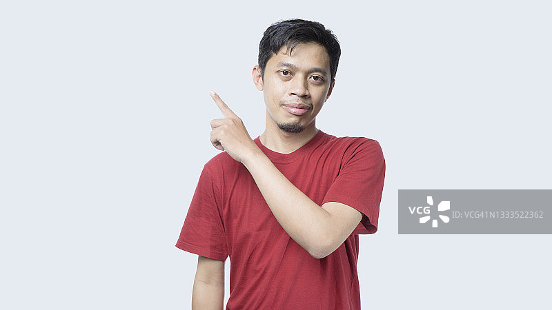 身穿红色T恤向上指的亚洲年轻男子图片素材