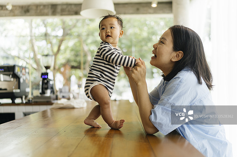 亚洲母亲支持女儿第一次站立和走路的幸福抓拍图片素材