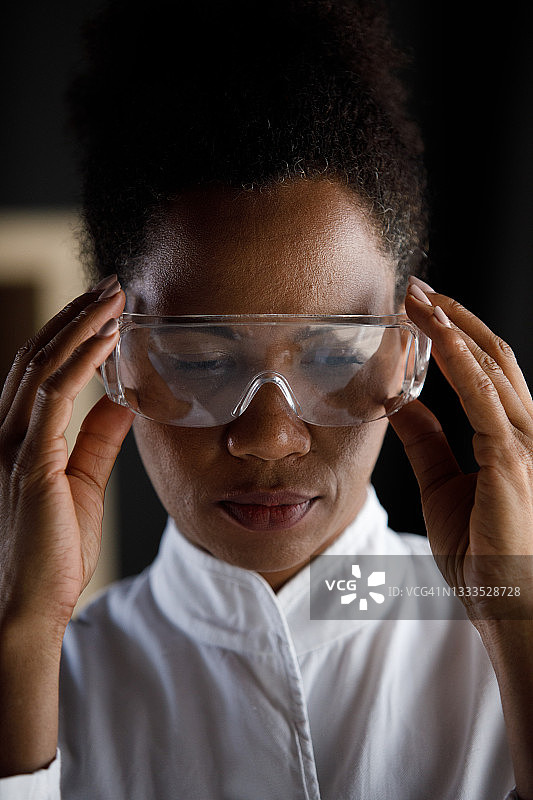 女科学家在实验室工作前戴上防护眼镜图片素材