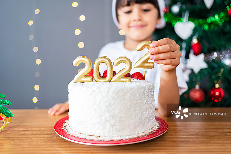 孩子在家装饰带有2022数字蜡烛的圣诞蛋糕图片素材