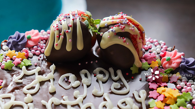 巧克力蛋糕特写，顶部有蘸巧克力草莓和彩色糖屑图片素材