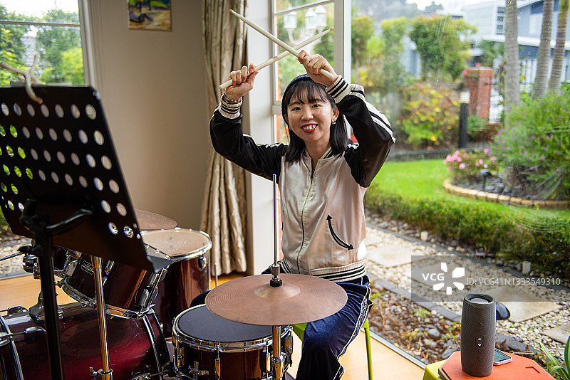 年轻的亚洲女鼓手在家练习图片素材