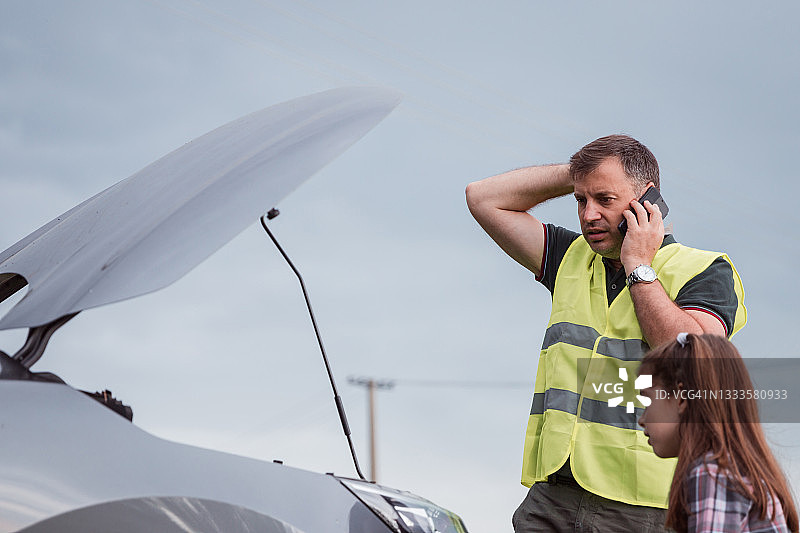 身穿高能见度背心的男子呼叫路边救援图片素材