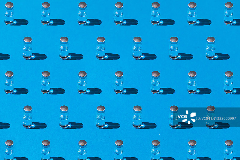 蓝色背景上的新冠疫苗药瓶硬阴影图案图片素材