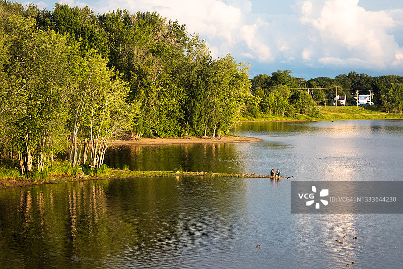 在加拿大新不伦瑞克省弗雷德里克顿的平静的圣约翰河上日落时钓鱼图片素材