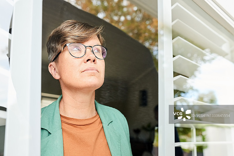 在家中窗边站立的沉思女人图片素材