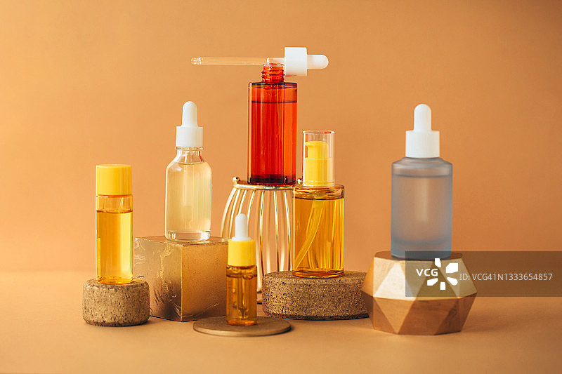 米色背景金色展台上的多色精华液玻璃瓶图片素材