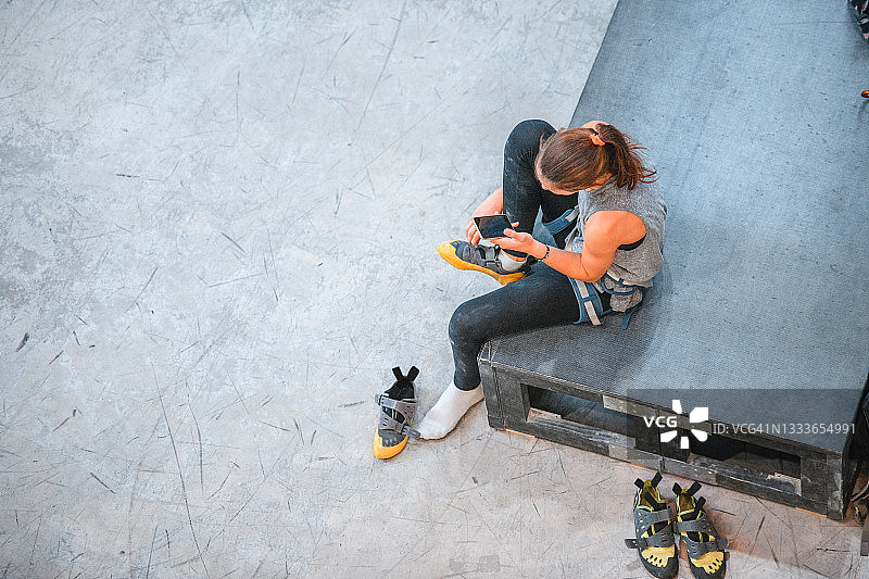 少女脱攀岩鞋并查看智能手机图片素材