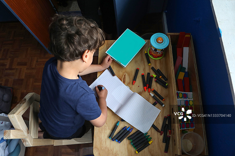 一个四岁男孩用蜡笔画画图片素材