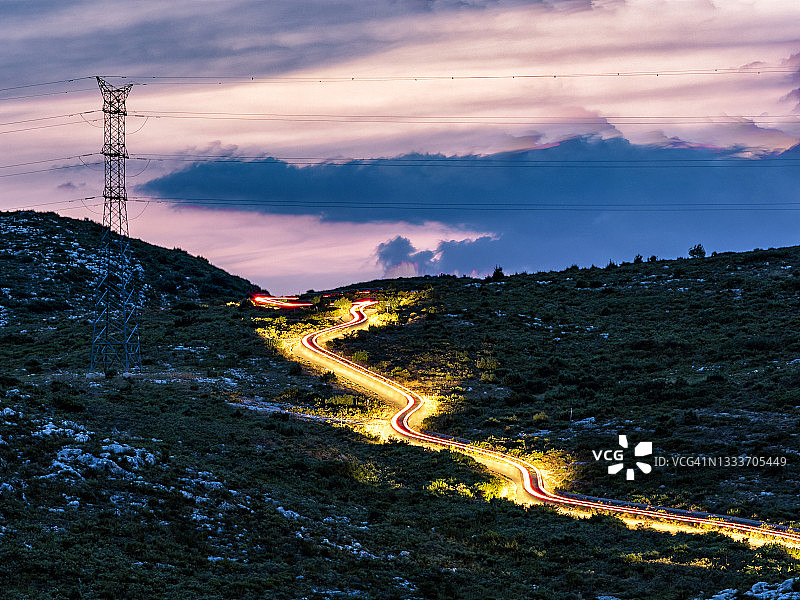 日落时分，汽车在蜿蜒山路上行驶的光轨图片素材