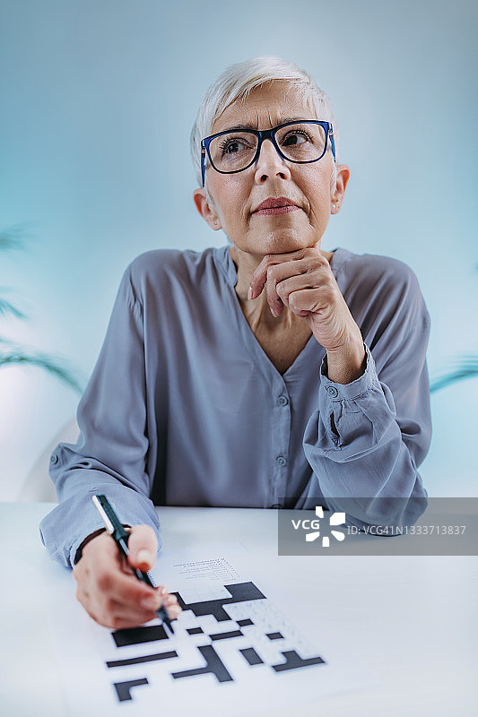 年长的女人在解纵横字谜图片素材
