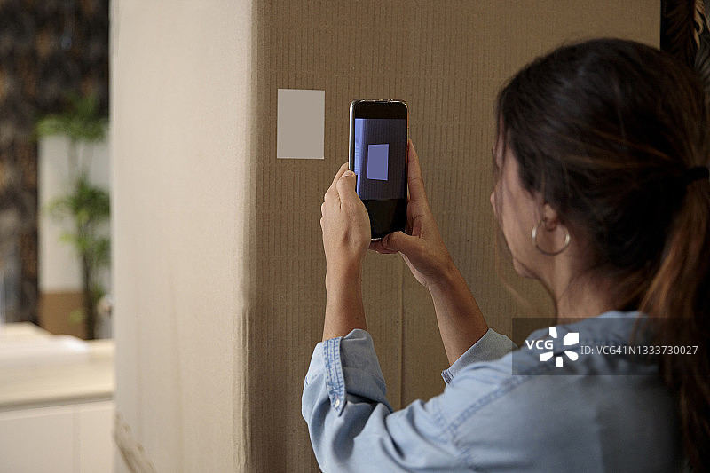 女人用智能手机扫描包裹上的送货信息图片素材