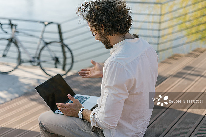 沮丧的年轻商人坐在楼梯上修理笔记本电脑图片素材