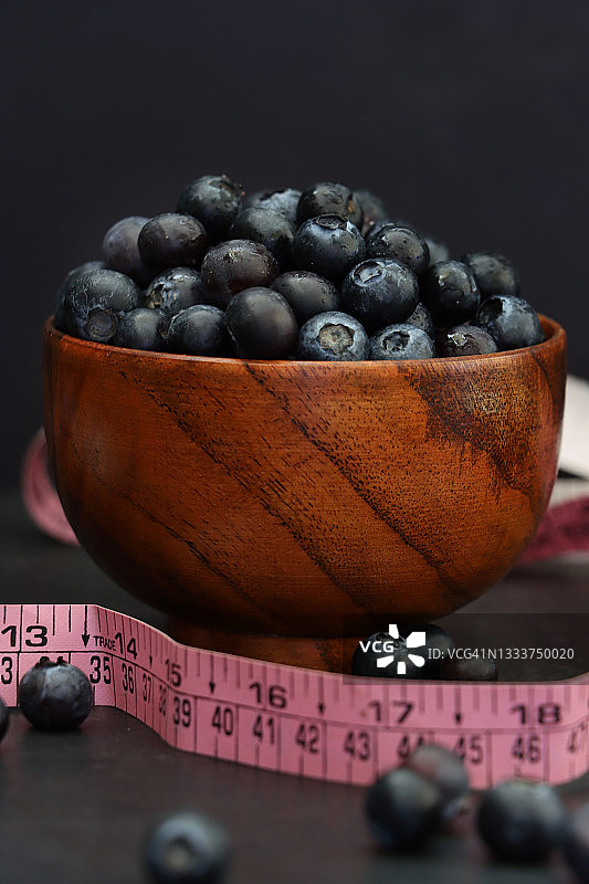 新鲜蓝莓：健康零食，木碗中堆满蓝莓图片素材