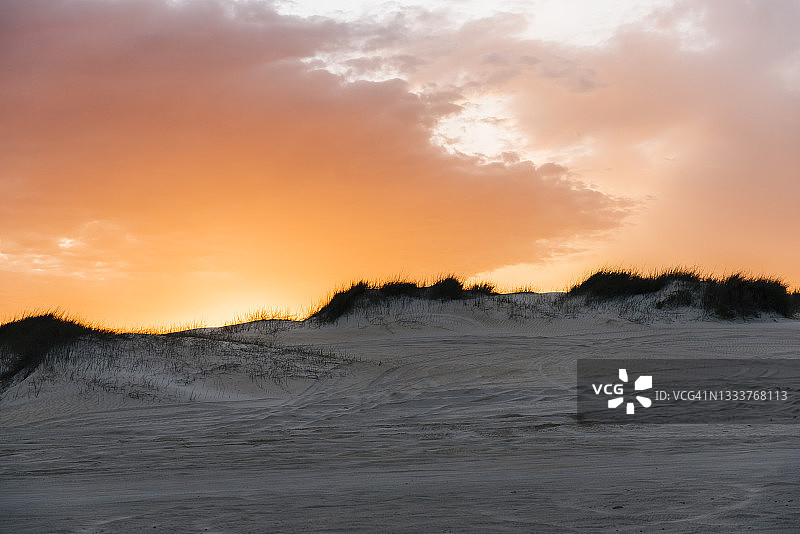 沙丘景观上的亮橙色日落图片素材