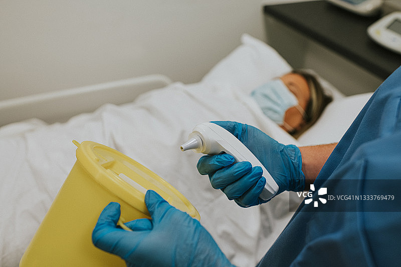 一名医生正在处理红外耳温枪上的塑料帽图片素材