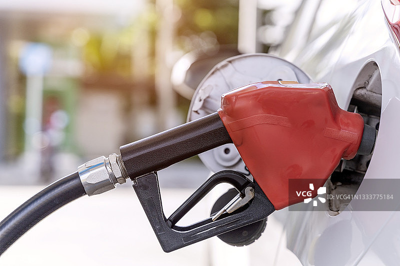 加油站手持加油枪给汽车加油，燃油监控系统特写。图片素材