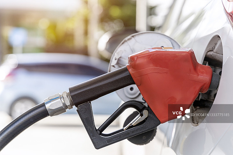 加油站手持加油枪给汽车加油，燃油监控系统特写。图片素材