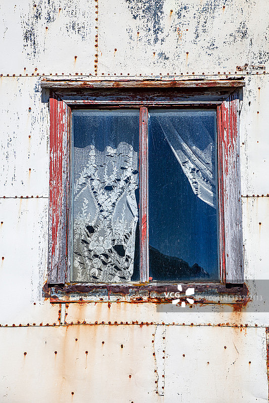 金属板废弃农舍风化窗框和蕾丝窗帘特写图片素材