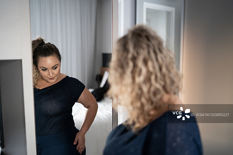 在家里对着镜子穿衣服的漂亮女人图片素材