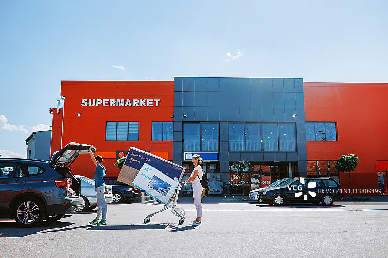 母子将大电视机搬到车上图片素材