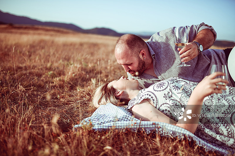 在野餐约会期间，疯狂的男人试图用香槟喂女友图片素材