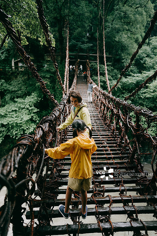 母亲和孩子穿过日本四国祖谷的藤桥图片素材