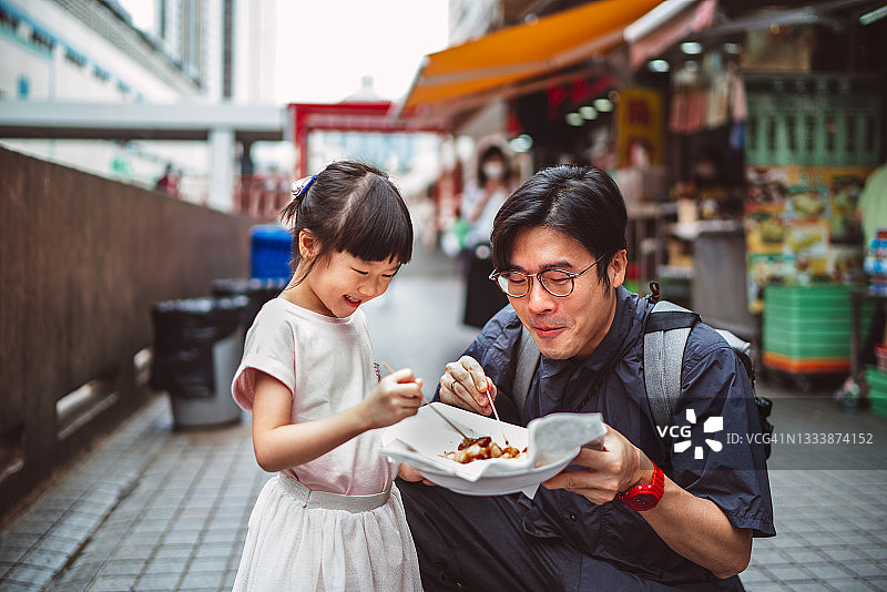 父女在香港街头愉快享用当地美食图片素材
