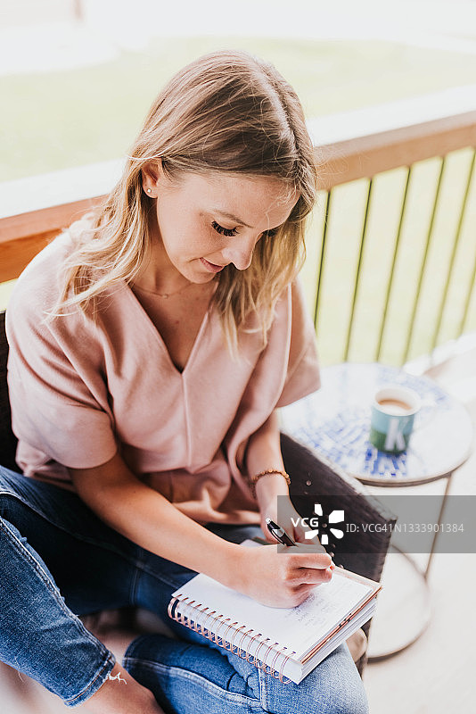 在门廊外笔记本上写字的女人图片素材