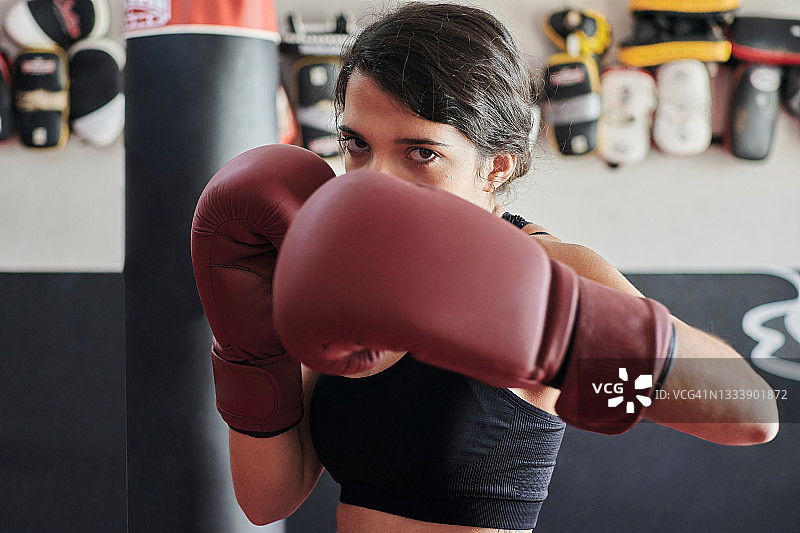 戴着拳击手套训练并看着镜头的女人图片素材